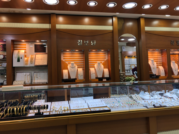 Ein Schmuckgeschäft mit Glasvitrinen voller Ketten, Ohrringe und Armbönder, sowie Schaufensterpuppen, die den Schmuck tragen, alles beleuchtet von Deckenlampen.