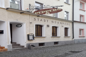 Gebäude mit "Stadt Nurnberg"-Schriftzug, Fenstern, Tür, Treppe und einem Müllimer im Vordergrund.