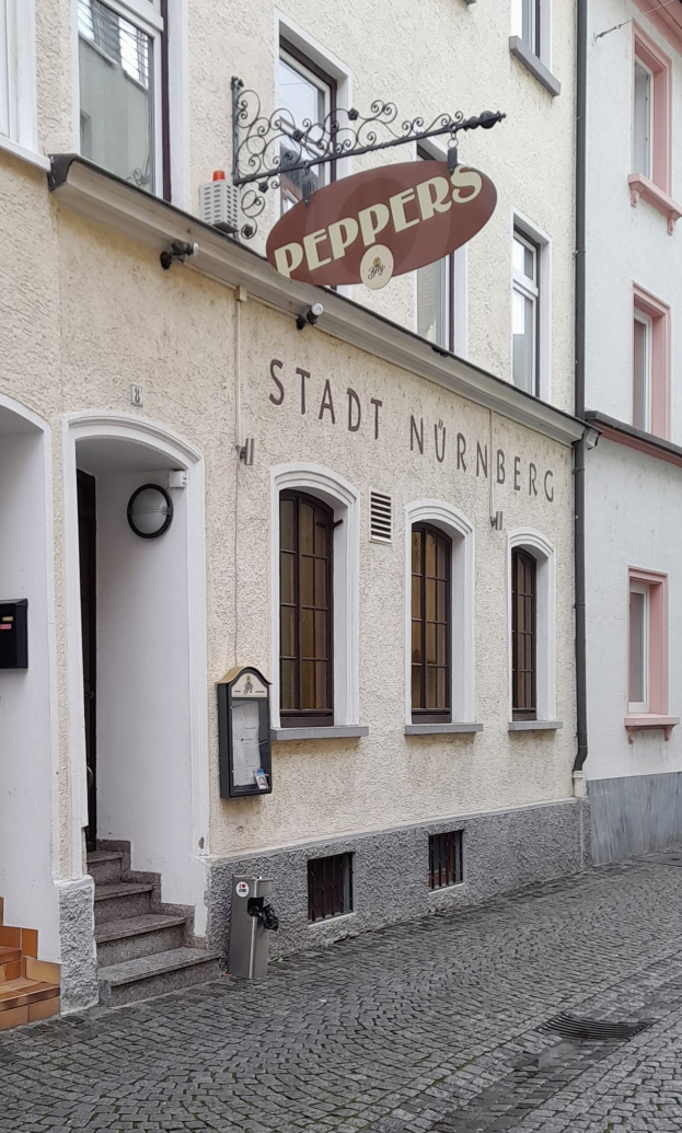 Gebäude mit "Stadt Nurnberg"-Schriftzug, Fenstern, Tür, Treppe und einem Müllimer im Vordergrund.