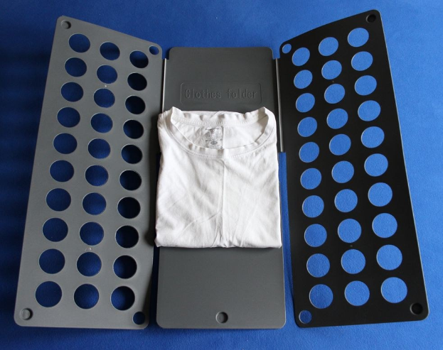 Ein weißes T-Shirt auf einer blauen Oberfläche neben einem schwarzen und aschgrauen Kleiderordner mit Löchern.