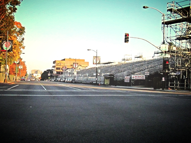 Eine Straße mit einer Ampelstange und Gerät auf der rechten Seite, Warnschilder und mehrere Fahrzeuge auf der linken Seite und Bäume im Hintergrund.