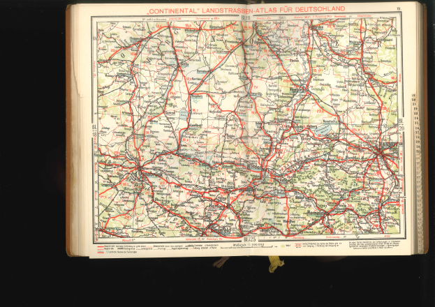 Ein aufgeschlagenes Buch mit einer detaillierten Deutschlandkarte mit Straßen und Autobahnen auf einem schwarzen Hintergrund.