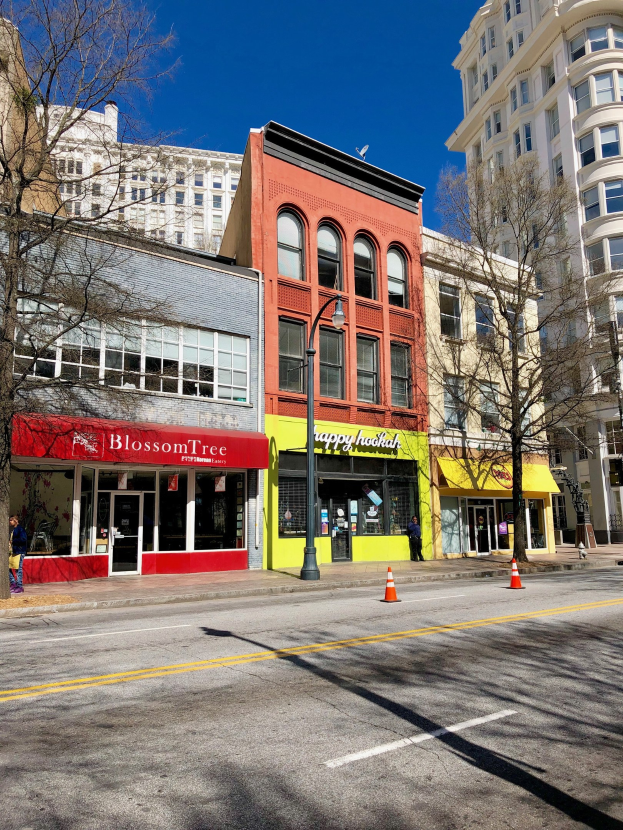 Eine Stadtstraße in Downtown Portland mit hohen Gebäuden, Fahrzeugen, Fußgängern, Bäumen und Absperrgittern.
