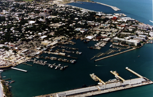 Eine Übersicht einer Stadt mit zahlreichen Gebäuden und Meerwasser, die einen Hafen mit Schiffen an der vorderen Unterseite zeigt.