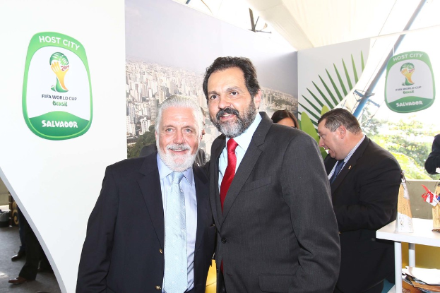 Eine Gruppe von Menschen, die mit einigen, die lächeln, und einem FIFA-WM-Plakat im Hintergrund steht.