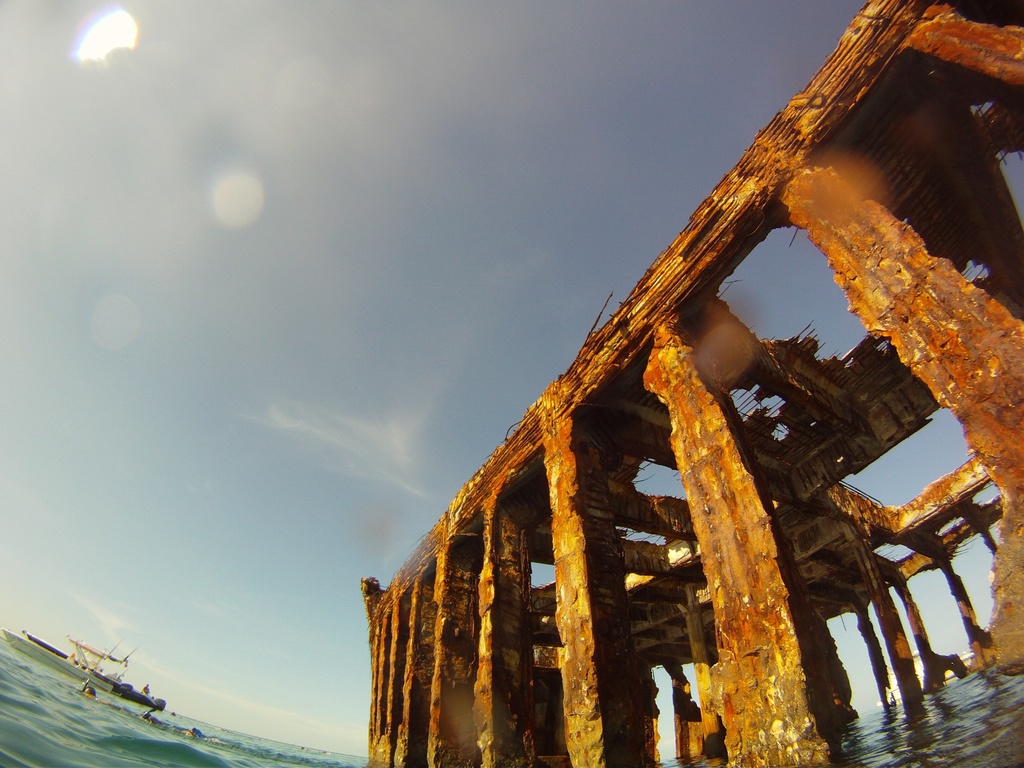 Ein Schiff befindet sich auf dem Wasser im linken unteren Bildviertel, mit einem hölzernen Dock auf der rechten Seite.