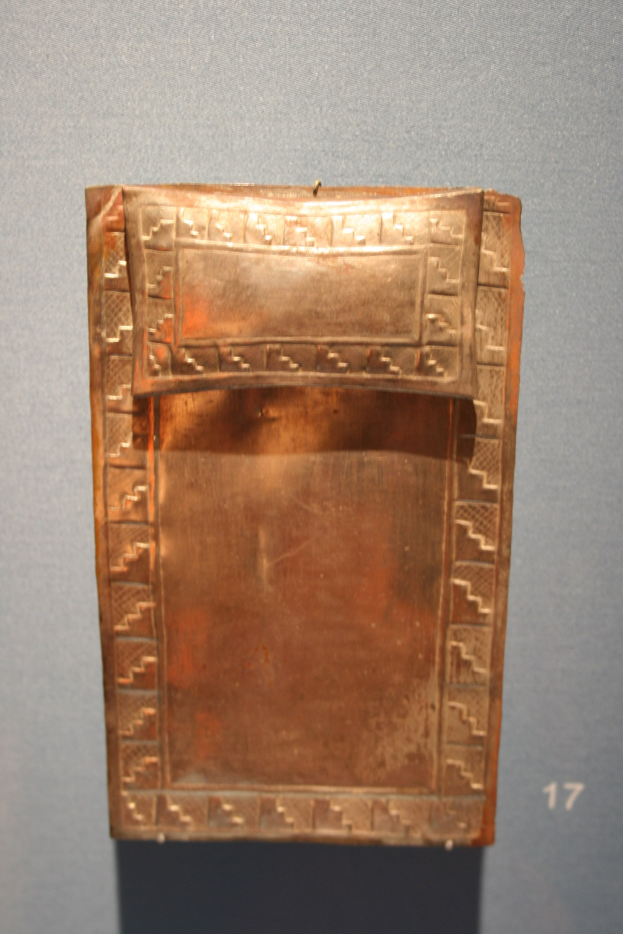 Kupferplatte mit detaillierten Designs in einem Museum ausgestellt, vor einer Wand mit einer sichtbaren Zahl auf der rechten Seite.