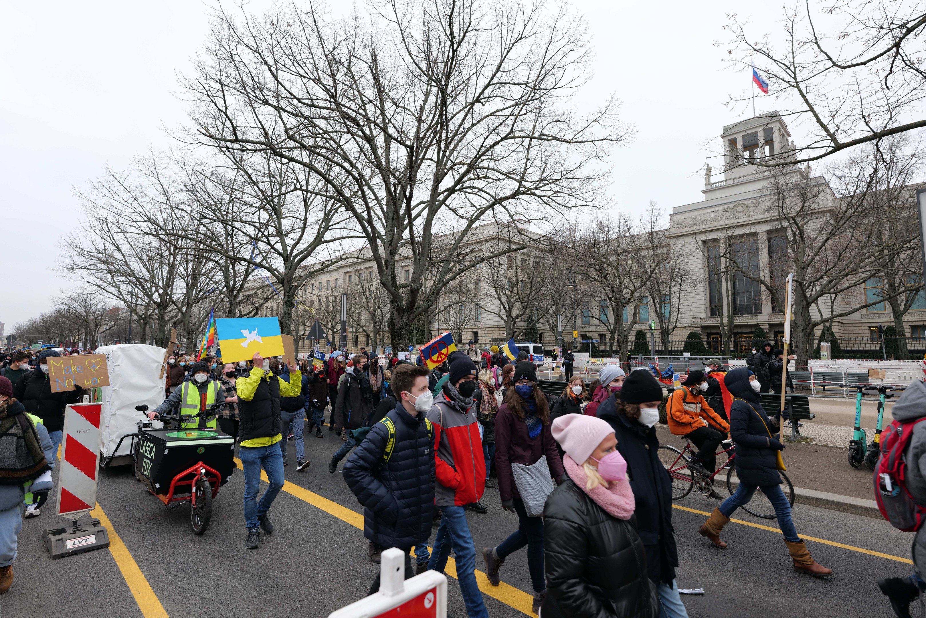 Eine große Gruppe von Menschen bei einer Demonstration auf einer Straße in Washington, D.C., mit Schildern, Fahrrädern, Bäumen, Schilderständen und einem klaren blauen Himmel im Hintergrund am 21. Januar 2020.