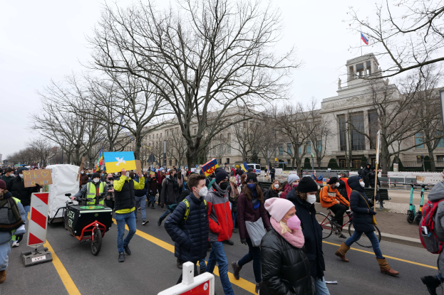 Eine große Gruppe von Menschen bei einer Demonstration auf einer Straße in Washington, D.C., mit Schildern, Fahrrädern, Bäumen, Schilderständen und einem klaren blauen Himmel im Hintergrund am 21. Januar 2020.