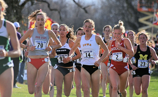 Eine Gruppe von Mädchen, die auf dem Boden läuft, alle tragen Abzeichen auf ihren Kleidern, mit Bäumen im Hintergrund.