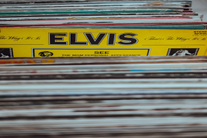 Ein ordentlich gestapelter Stapel Elvis-Presley-Platten auf einem Tisch, mit einigen Titeln und einem leicht unscharfen, träumerischen Hintergrund.
