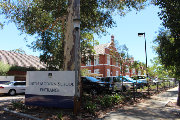 Eintritt zum Perth Modern School mit einem Schild, Bäumen, Pflanzen, einem Zaun, einem Straßenschild, geparkten Autos, Gebäuden mit Fenstern und einem bewölkten Himmel.
