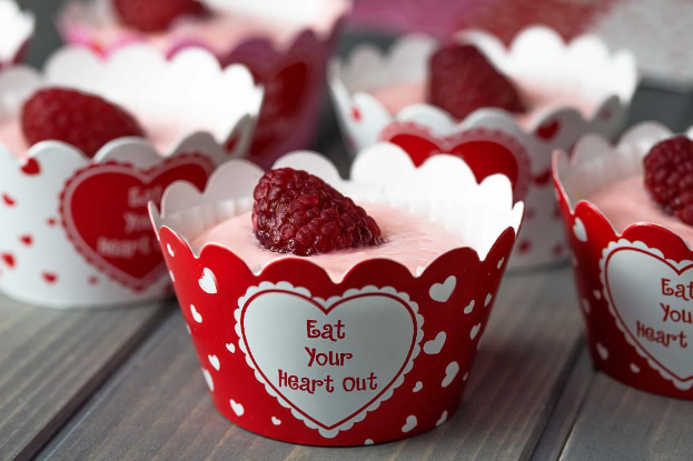 Ein Tisch mit mehreren Bechern Eiscreme, jeder mit einer Erdbeere obendrauf.