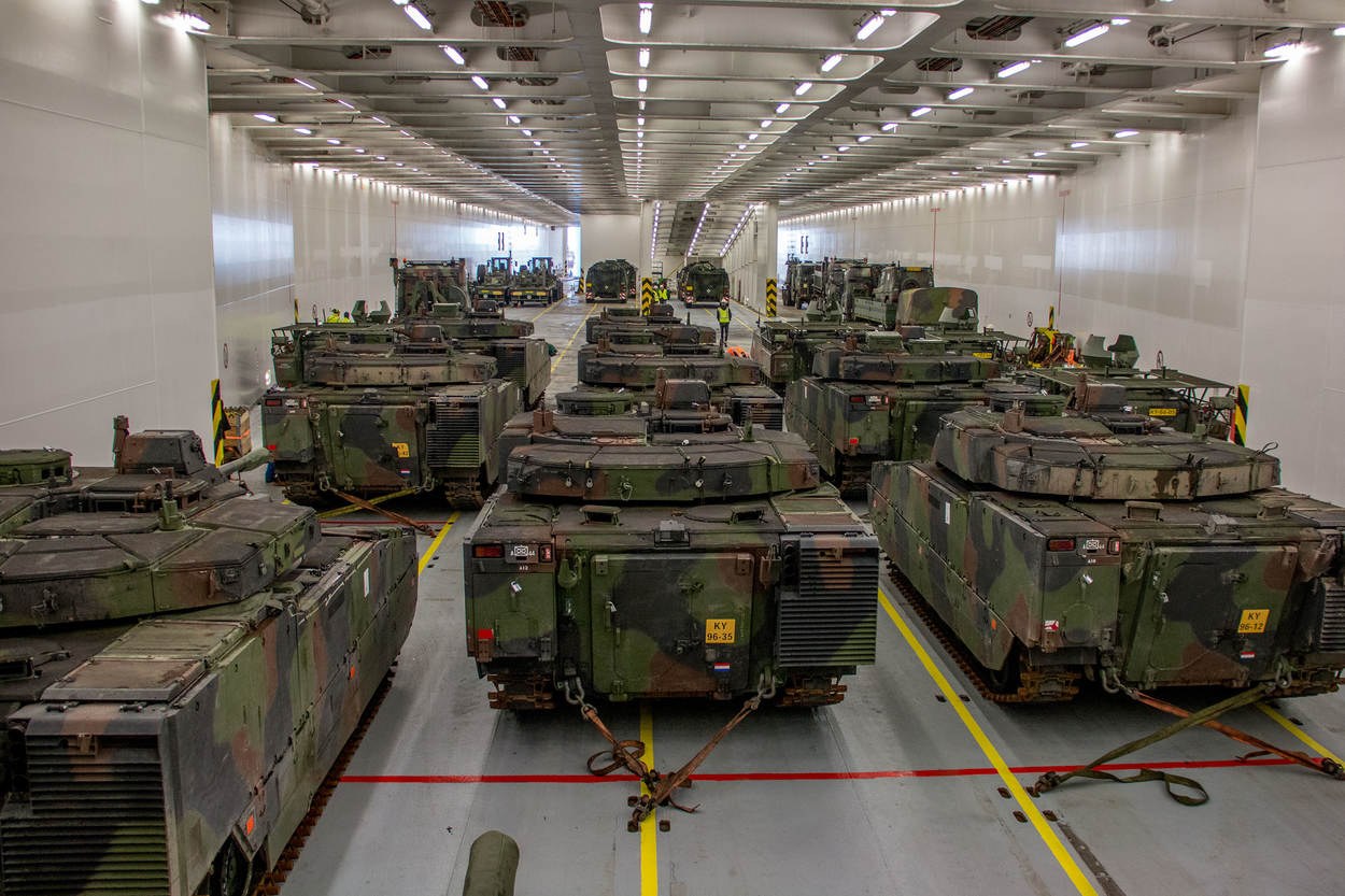 Ein grosser Militaraustellungsraum mit Reihen von Militaraerzten, beleuchtet von Deckenleuchten und von Waenden umgeben.