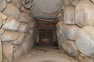 Ein Tunnel voller Steine und ein Metalltor in der Mitte, mit Drähten an der Oberseite, die an einen Minenschacht erinnern.