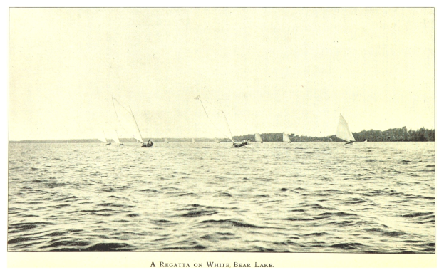 Regatta am Wei├čen Bär See mit Booten auf dem Wasser, Tieren im Hintergrund und Text unten.