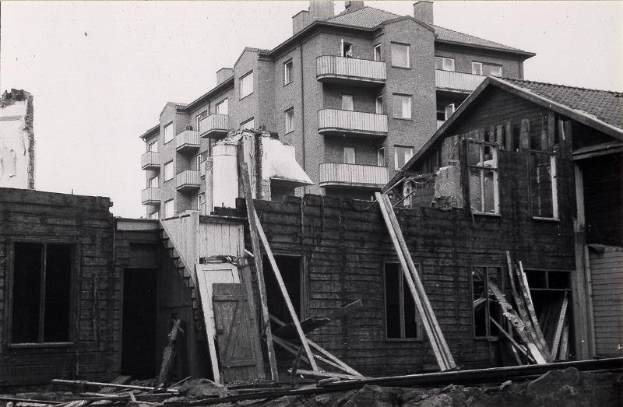 Ein Schwarz-Weiß-Foto der abgerissenen West End Apartments, mit Schutt auf dem Boden und dem Himmel im Hintergrund.