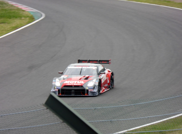 Nissan GT-R Nismo GT3-Rennwagen auf der Nürburgring 24 Stunden-Strecke, umgeben von grünem Gras auf beiden Seiten.
