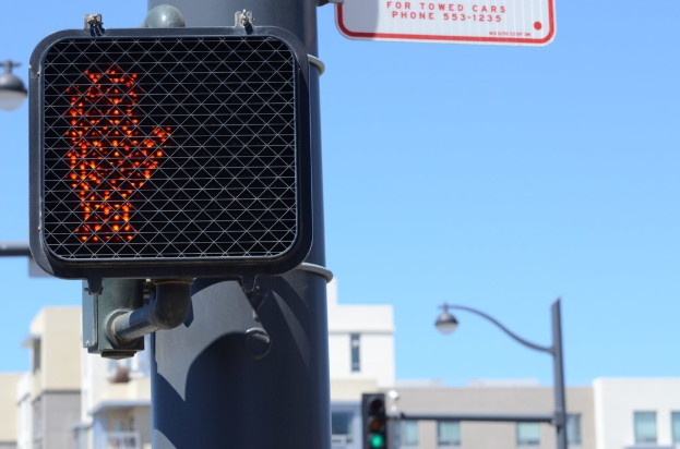 Eine Stadtstraßenszene mit Verkehrspfählen, Ampeln, Straßenlaternen, Gebäuden und einem klaren Himmel.