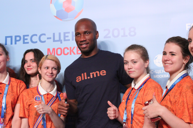 Eine Gruppe von Menschen auf einer Bühne mit einem Mann in der Mitte, der ein Mikrofon hält, hinter einem Banner mit dem Text und Logo der FIFA WM 2018.