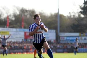 Ein Mann in einem blauen und weißen gestreiften Hemd rennt mit einem Fußball auf einem Rasenfeld während eines Huddersfield Town v Swansea City-Spiels in der Sky Bet Championship. Im Hintergrund sind Zuschauer, Schilder, Fahnen und Bäume unter einem klaren blauen Himmel zu sehen.