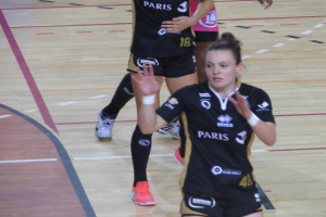 Eine Gruppe von Frauen in Sportkleidung beim Volleyballspielen auf einem Feld.