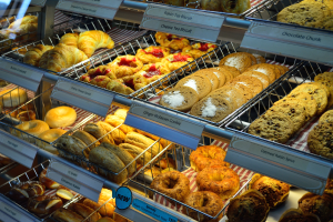 Ein Bäckereischaufenster voller verschiedener Kuchen, Torten, Kekse und andere Backwaren, mit Schildern, die die Art der Backwaren angeben.