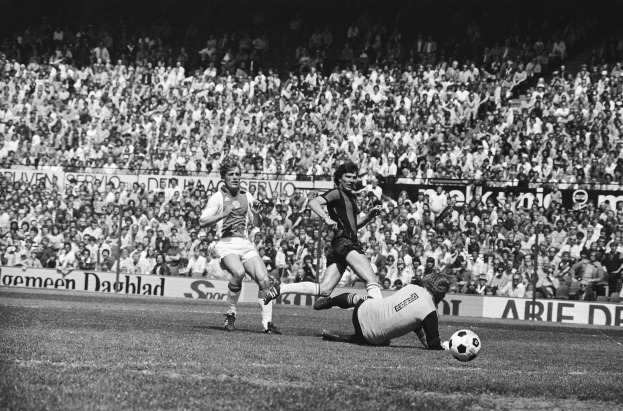 Schwarzes und weißes Bild von Männern, die auf einem Feld Fußball spielen, mit Zuschauern im Hintergrund und einer Tafel mit der Aufschrift "Bundesliga 1978-79 Ajax 1-1 Hannover 96"
