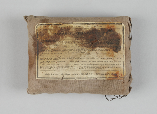 Kleiner Verbandkasten mit einem informativen Blatt obenauf.