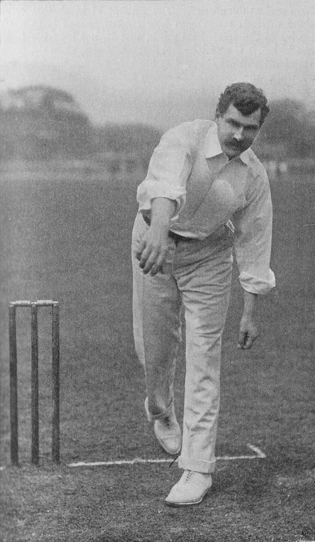 Ein Mann in weißer Cricket-Uniform spielt in einem Match mit Wickets auf dem Boden, Bäumen und Himmel im Hintergrund, mit dem Text "Cricket-Spieler des Jahres" unten.
