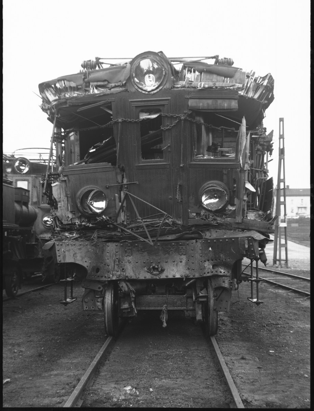 Schwarz-weiß-Foto eines alten, verrosteten Zuges auf Schienen mit einer Leiter auf der rechten Seite und einem Gebäude im Hintergrund.