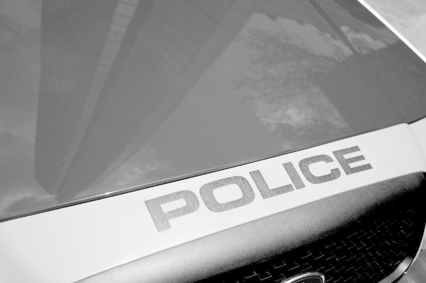 Ein Polizeifahrzeug mit einer Spiegelung eines Gebäudes und Baums auf seiner Oberfläche.