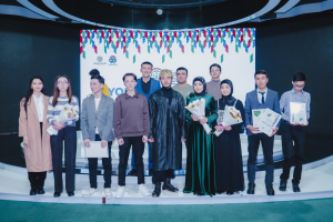 Gruppe von Menschen auf einer Bühne mit Blumensträußen und Urkunden vor einem "Youth Solar Awards 2019"-Plakat.