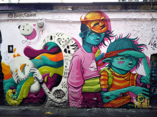 Mit Graffiti bedecktes Geb%C3%A4ude, Straße im Vordergrund, Strommasten und klarer blauer Himmel im Hintergrund.