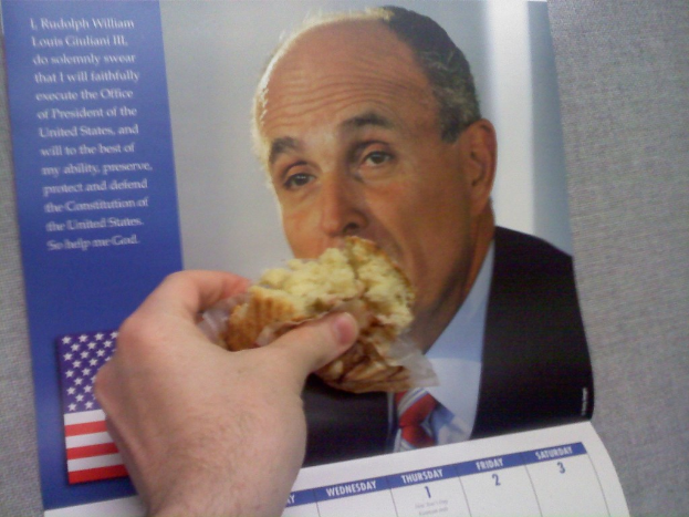 Ein Kalender mit einem Foto in der Mitte, auf dem eine Hand mit einem Kuchen darauf zu sehen ist.