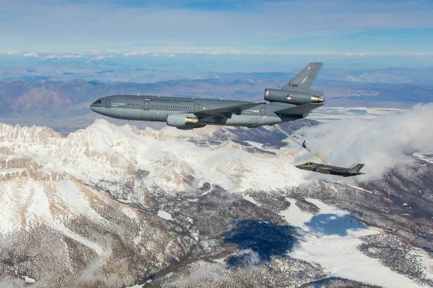 Ein KC-135R Stratotanker tankt einen B-52H Stratofortress im Flug über ein verschneites Gebirge, mit Wolken am Himmel und einem Wasserzeichen auf dem Bild.