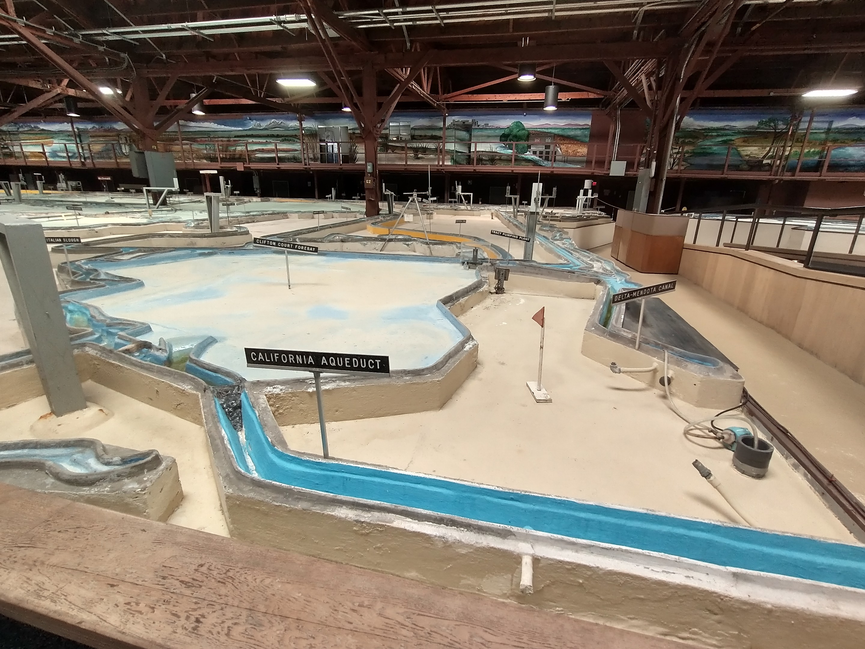Großes Indoor-Wasserpark mit mehreren Wasserrutschen, Deckenleuchten, Wandgemälden und einem Minigolfplatz.