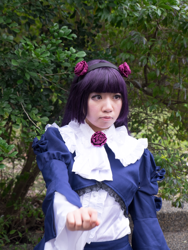 Eine Frau mit lila Haaren in einem blauen und weißen Kleid steht vor einem Hintergrund aus Bäumen, mit dem Text "Re:Zero Starting Life in Another World" unten im Bild.