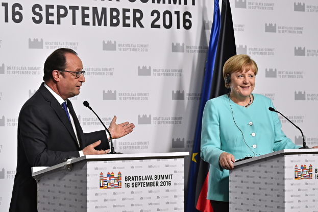 Bundeskanzlerin Angela Merkel und Frankreichs Präsident François Hollande stehen an Rednerpulten mit Mikrofonen, lächeln, mit einem 'Bratislava-Gipfel 2016'-Plakat im Hintergrund.