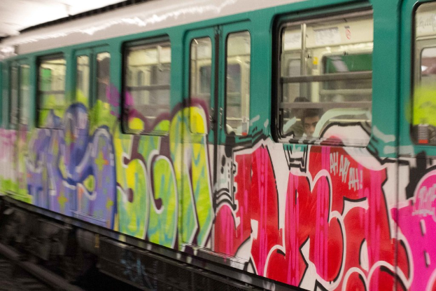 Ein Zug auf Eisenbahnschienen mit zwei Personen darin und Graffiti an seiner Außenseite.