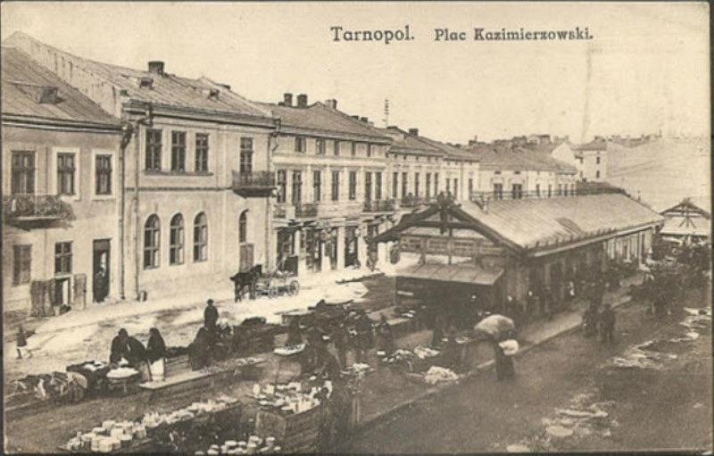 Schwarz-weiß-Foto eines vollen Marktes in Tarnopol, Polen mit Menschen auf Karren und Gebäuden im Hintergrund.