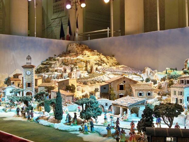 Ein detailliertes Miniatur-Modell einer Krippe in einem Museum ausgestellt, mit Figuren, Strukturen und Beleuchtungselementen.