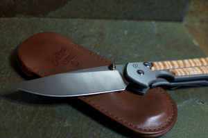 Ein Messer und ein Lederobjekt sind auf einer Oberfläche zu sehen.