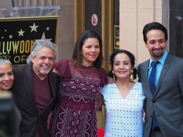 Gruppe von Menschen auf einem roten Teppich bei der Zeremonie des Hollywood Walk of Fame posierend, mit einer Tafel, einem Glaspodest und einer Wand im Hintergrund.