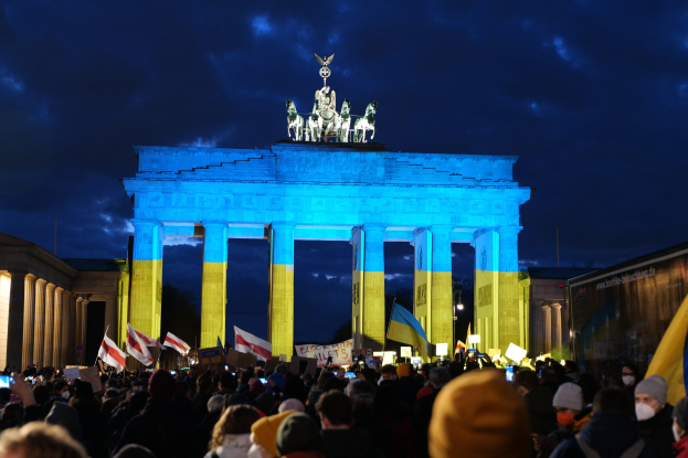 Eine Menschenmenge steht vor dem Brandenburger Tor in Berlin, Deutschland, mit Fahnen und Plakaten, auf denen ein Banner auf der rechten Seite zu sehen ist.